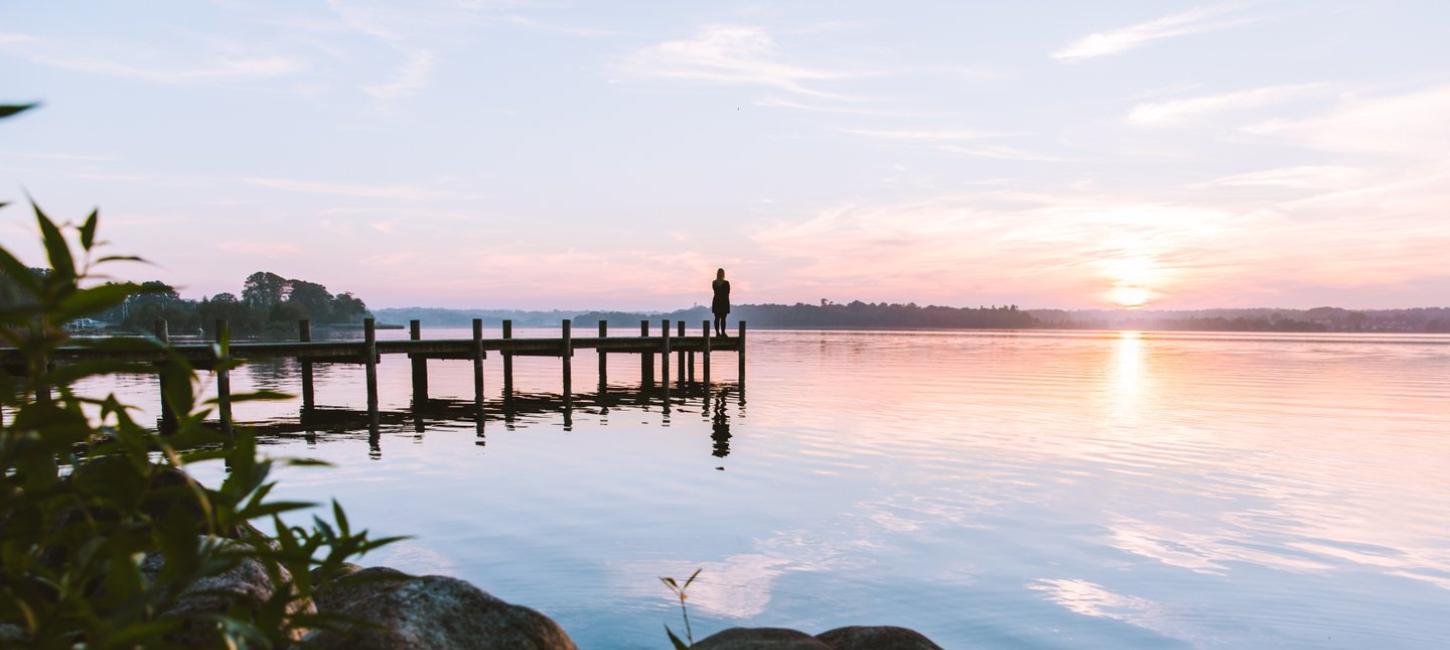 A person enjoying a sunrise on pier at Esrum Lake in North Zealand