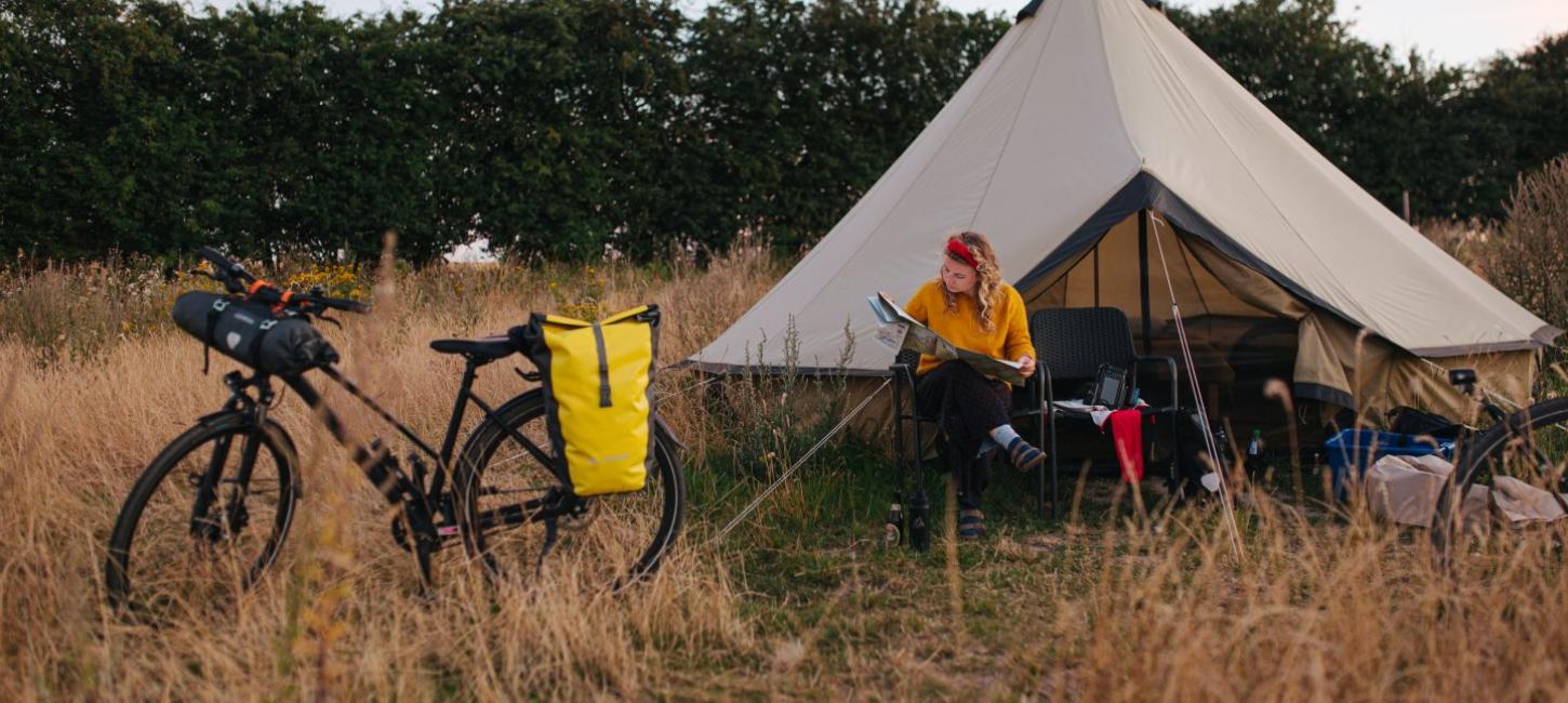 Kvinde foran telt og cykel