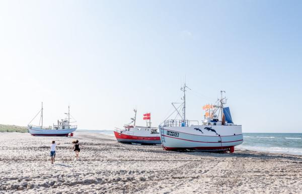 Kinder spielen an der dänischen Nordsee, Fischerboote liegen am Strand