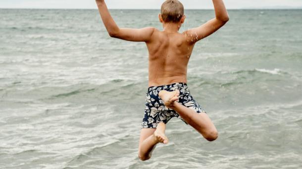 Children jumping into the water at Gilleleje Beach in North Zealand, Denmark