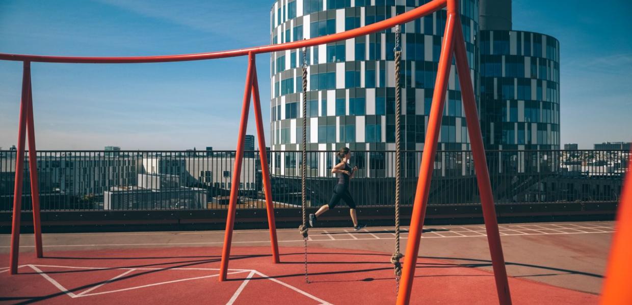 A lady running at the rooftop playground Konditaget Lüders in Nordhavn, Copenhagen, Denmark