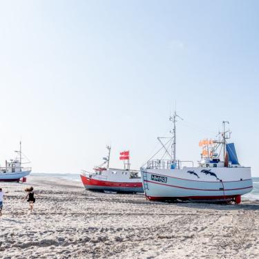 Kinder spielen an der dänischen Nordsee, Fischerboote liegen am Strand