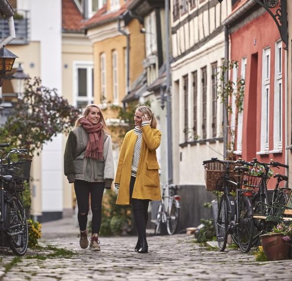 To kvinner går i Aalborgs gater på høsten