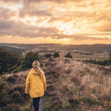 Mädchen in gelber Jacke läut im Sonnernuntergang durch Rebild Bakken, Dänemark